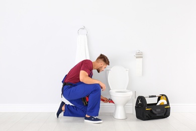 Photo of Young man working with toilet bowl in bathroom