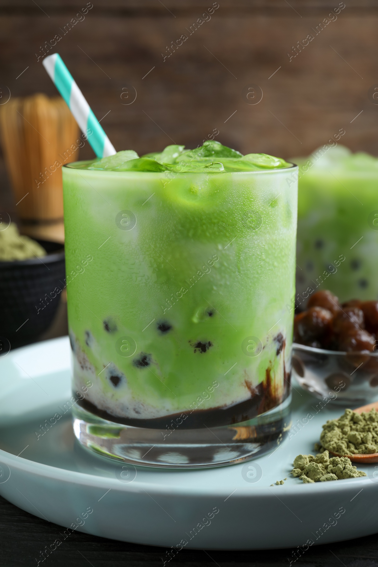 Photo of Tasty milk bubble tea with green matcha on blue plate, closeup