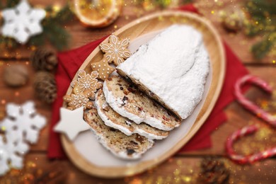 Traditional Christmas Stollen with icing sugar on wooden table, flat lay. Bokeh effect
