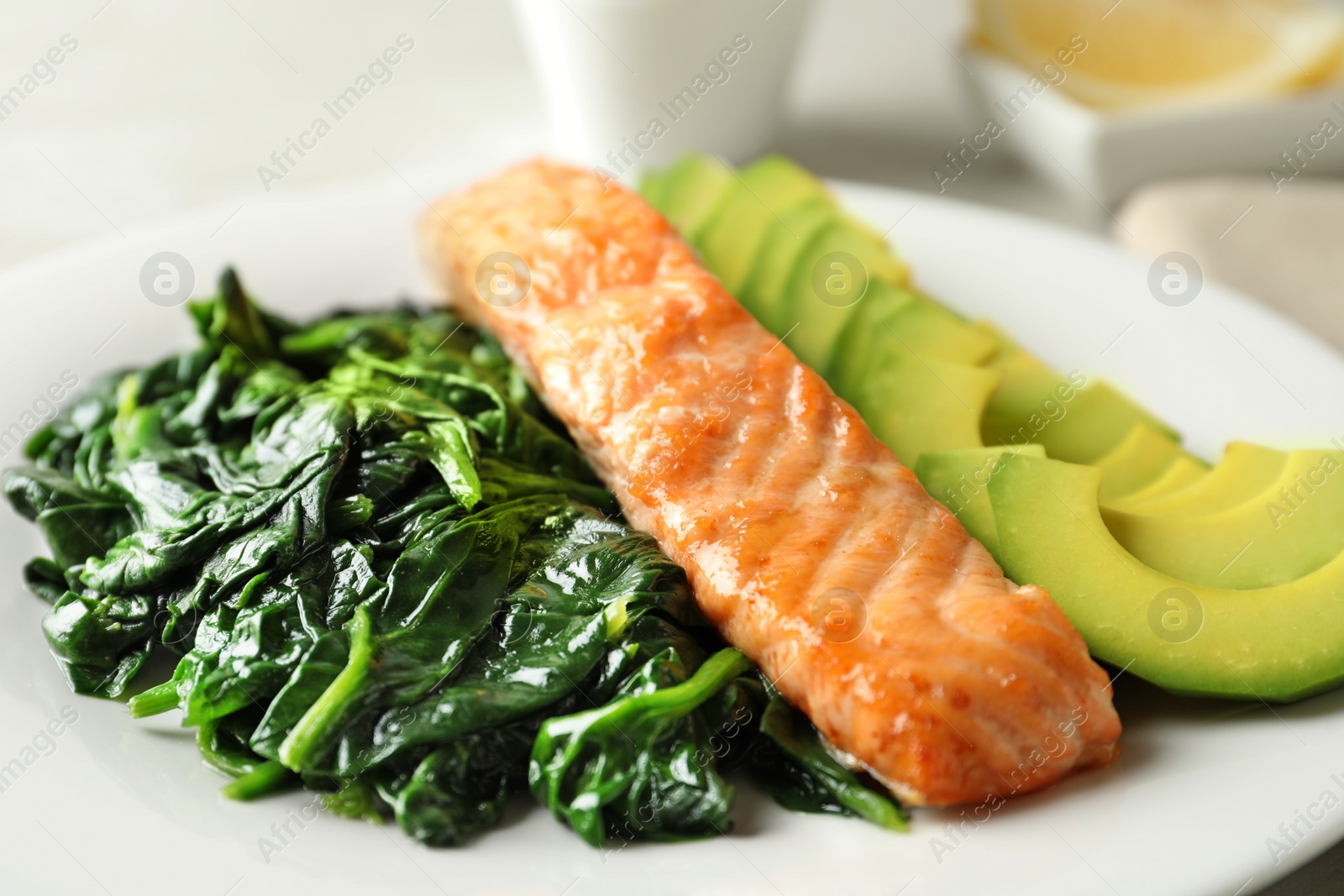 Photo of Tasty salmon with spinach and avocado on plate, closeup