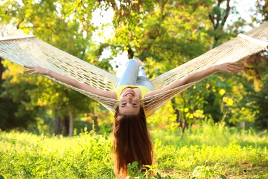 Photo of Young woman resting in comfortable hammock at green garden