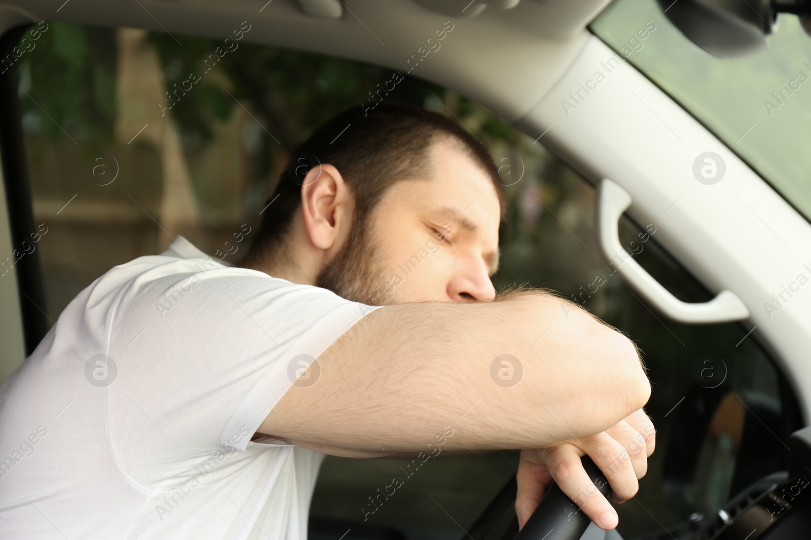 Photo of Tired man sleeping on steering wheel in his car