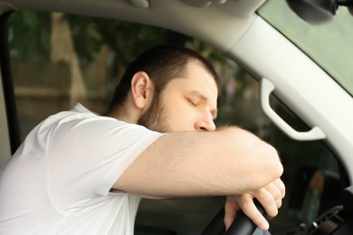 Photo of Tired man sleeping on steering wheel in his car