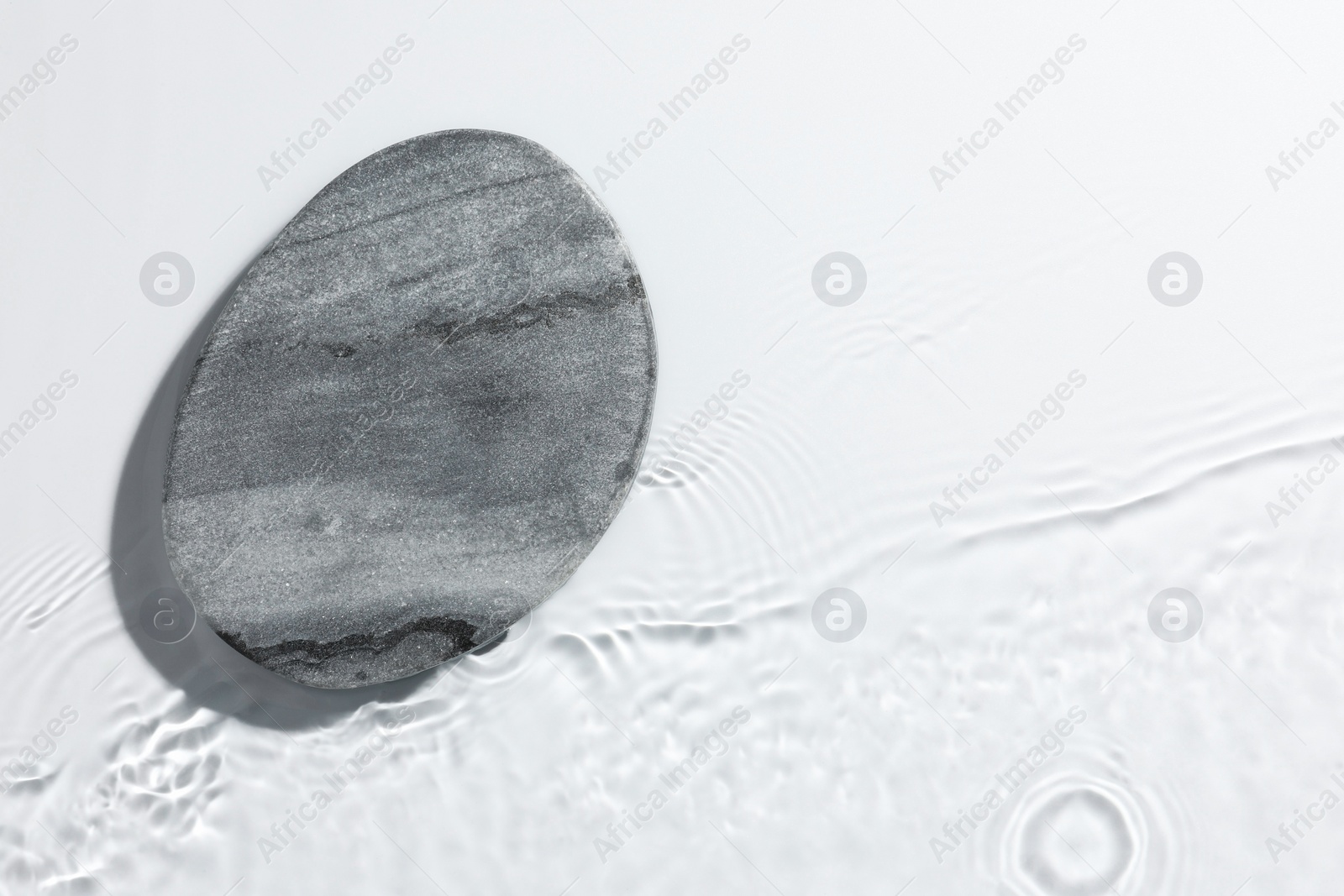 Photo of Presentation of product. Stone podium in water on white background, top view. Space for text