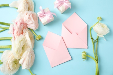 Photo of Flat lay composition with beautiful ranunculus flowers and envelopes on color background