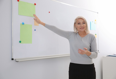 Mature teacher near whiteboard in modern classroom