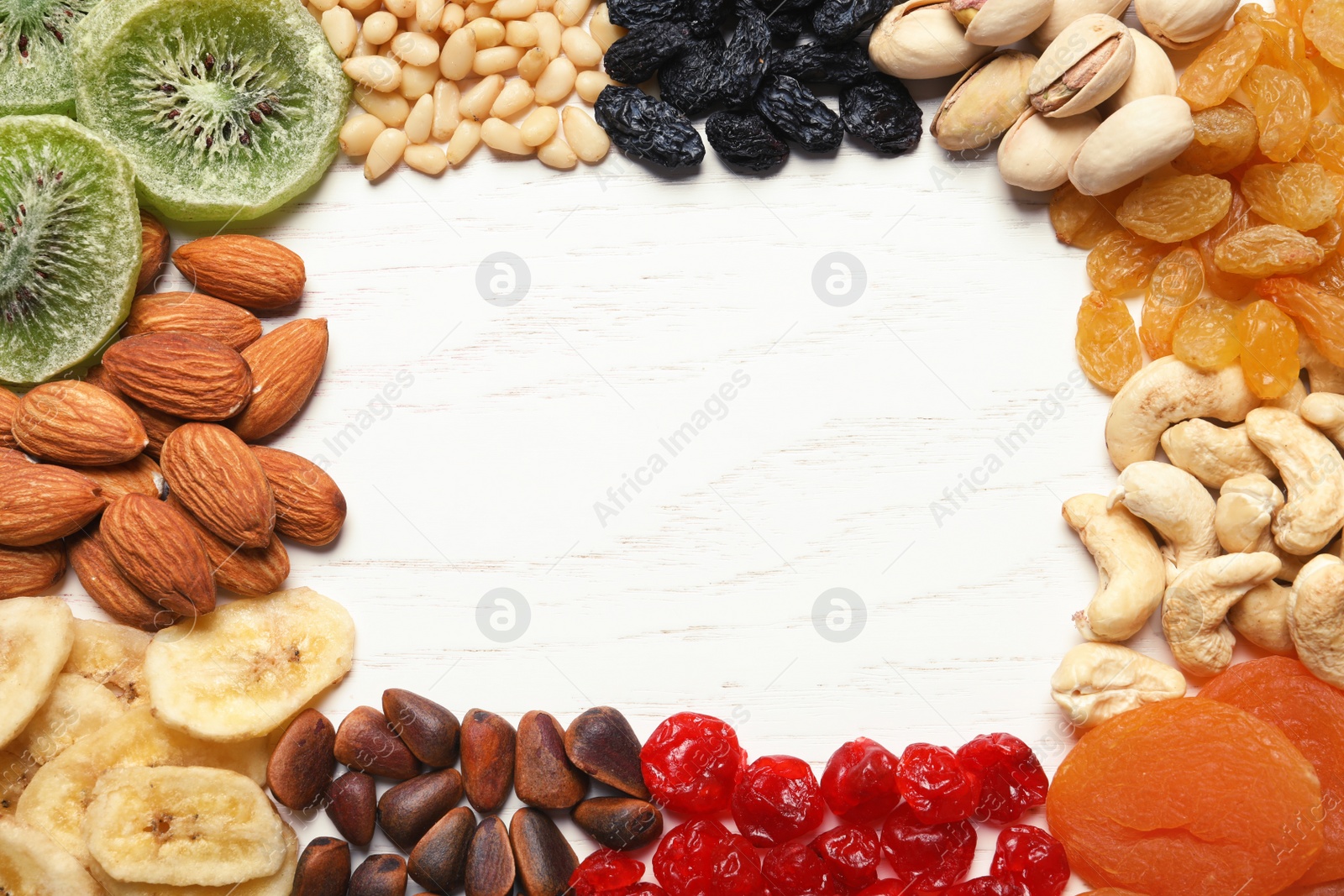 Photo of Frame of different dried fruits and nuts on wooden background, top view. Space for text