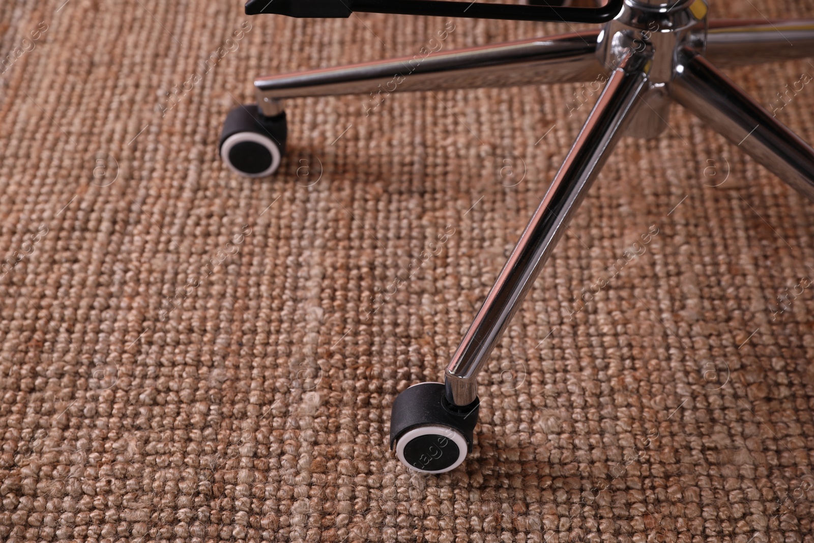 Photo of Modern office chair with wheels on floor, closeup