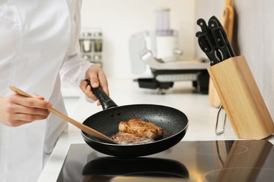 Photo of Chef cooking delicious meat with thyme in frying pan indoors, closeup