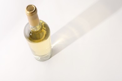 Bottle of expensive white wine on light background, above view. Space for text