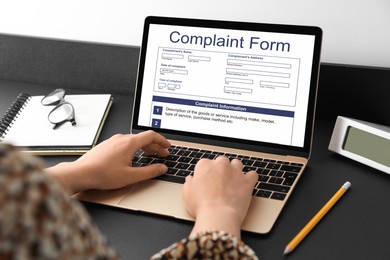 Image of Woman filling online complaint form via laptop at table, closeup