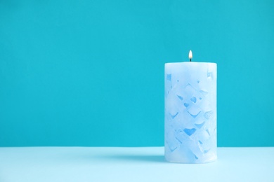 Photo of Alight wax candle on color background. Space for text