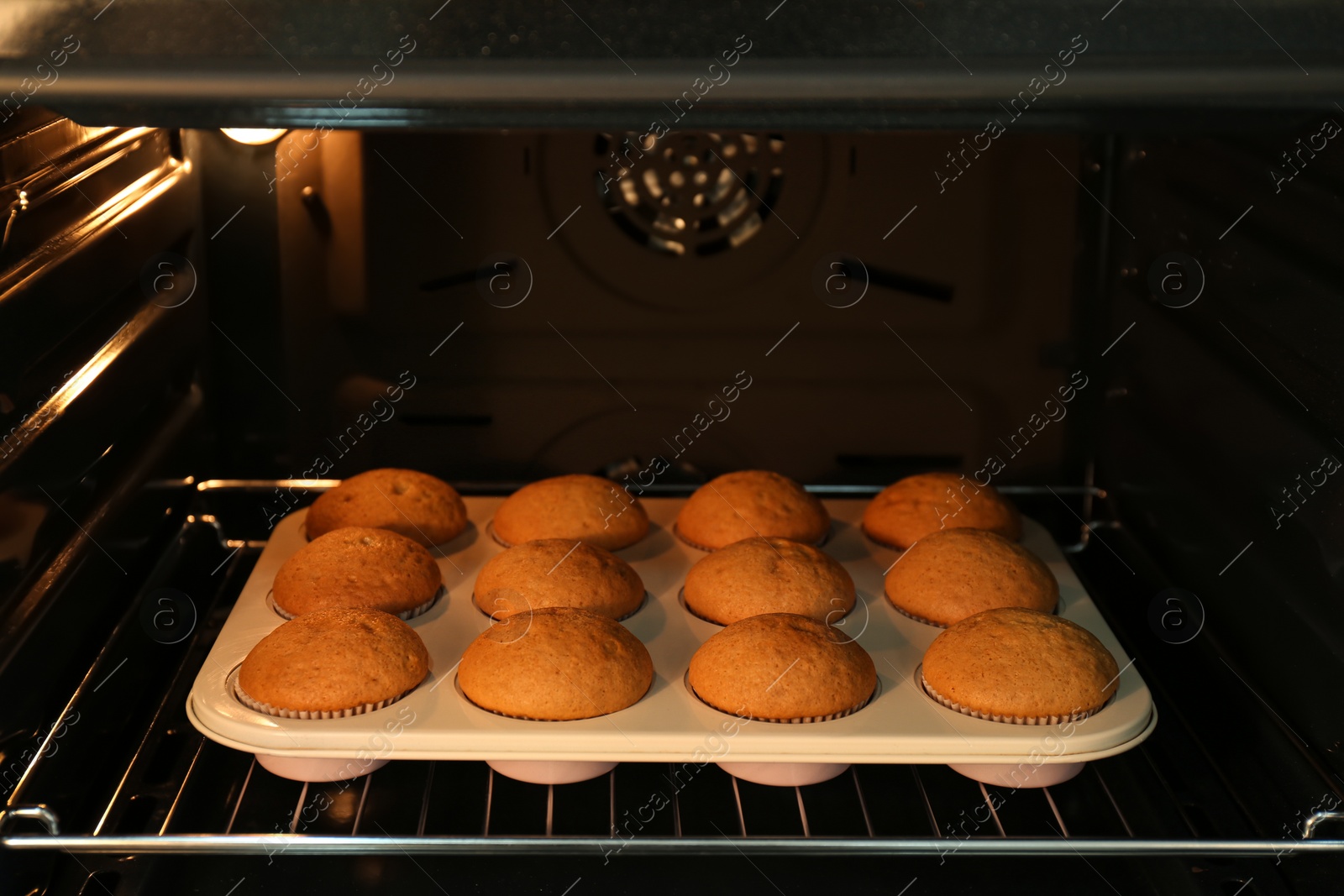 Photo of Baking pan with cupcakes in modern oven