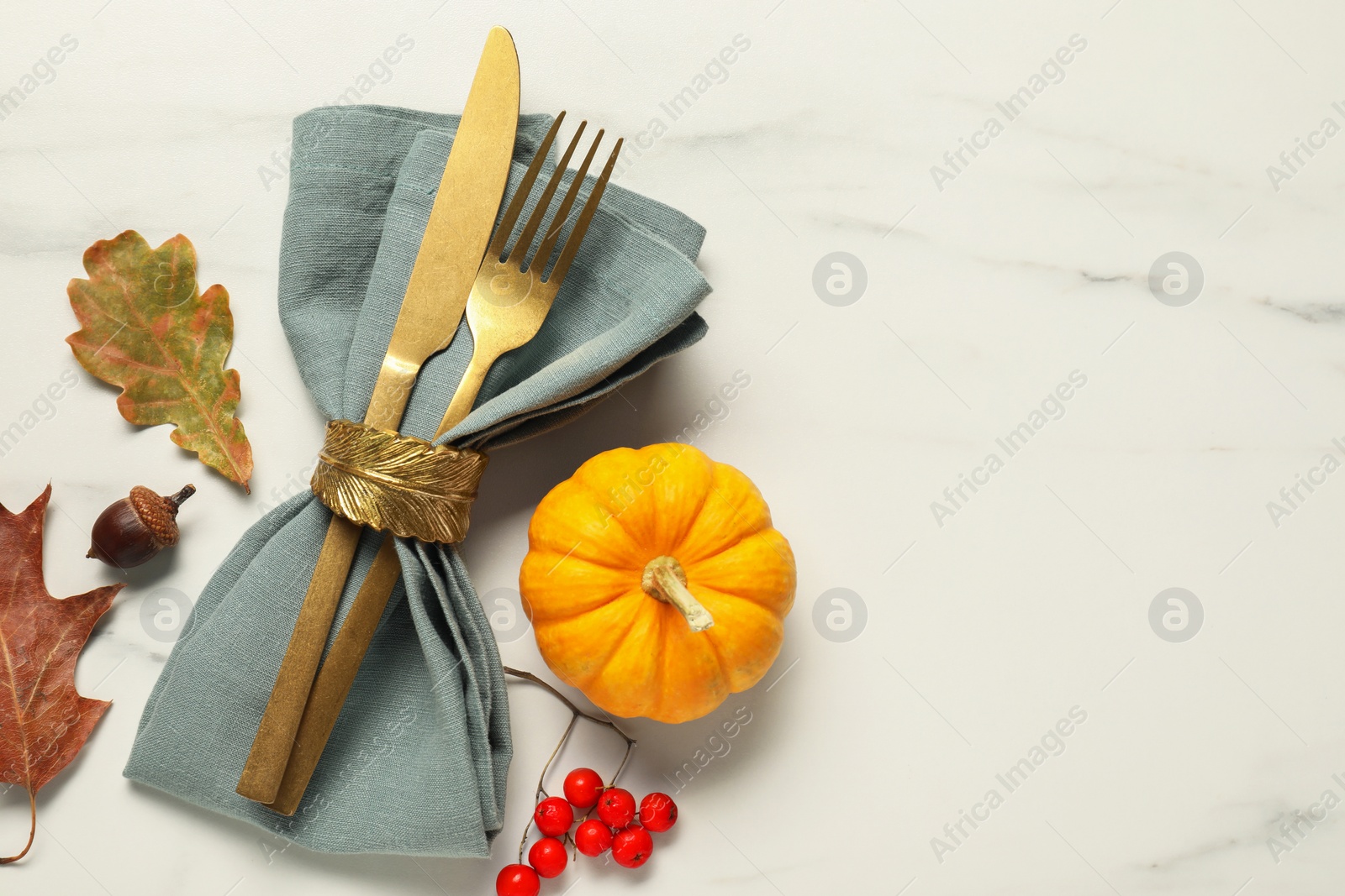 Photo of Cutlery, napkin and autumn decoration on white marble background, flat lay with space for text. Table setting