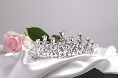 Photo of Beautiful silver tiara with diamonds and rose on white silk cloth