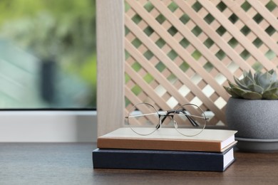 Photo of Books with glasses and houseplant on wooden window sill. Space for text