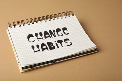 Photo of Open notebook with phrase Change Habits on brown background