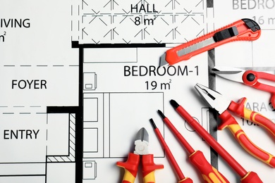 Flat lay composition with electrician's tools on house plan. Space for text