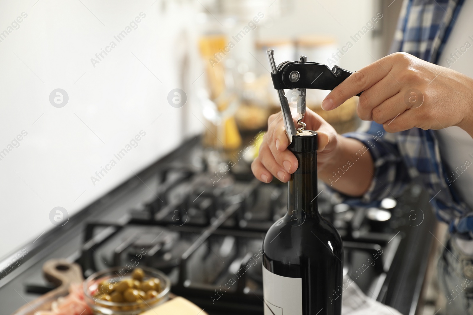 Photo of Woman opening wine bottle with corkscrew indoors, closeup. Space for text