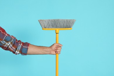 Photo of Man with yellow broom on light blue background, closeup