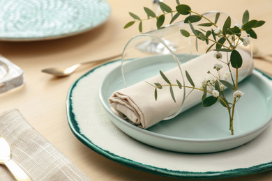 Photo of Elegant table setting with flowers and leaves, closeup