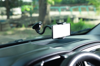 Photo of Car holder with modern mobile phone on windshield of automobile. Mockup for design