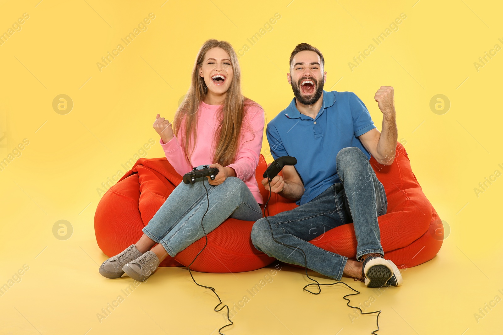 Photo of Emotional couple playing video games with controllers on color background