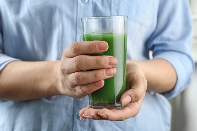 Photo of Woman holding glass of wheat grass juice, closeup