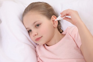 Little girl using ear drops in bed