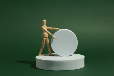 Product photography props. Round shaped podiums and wooden mannequin on green background