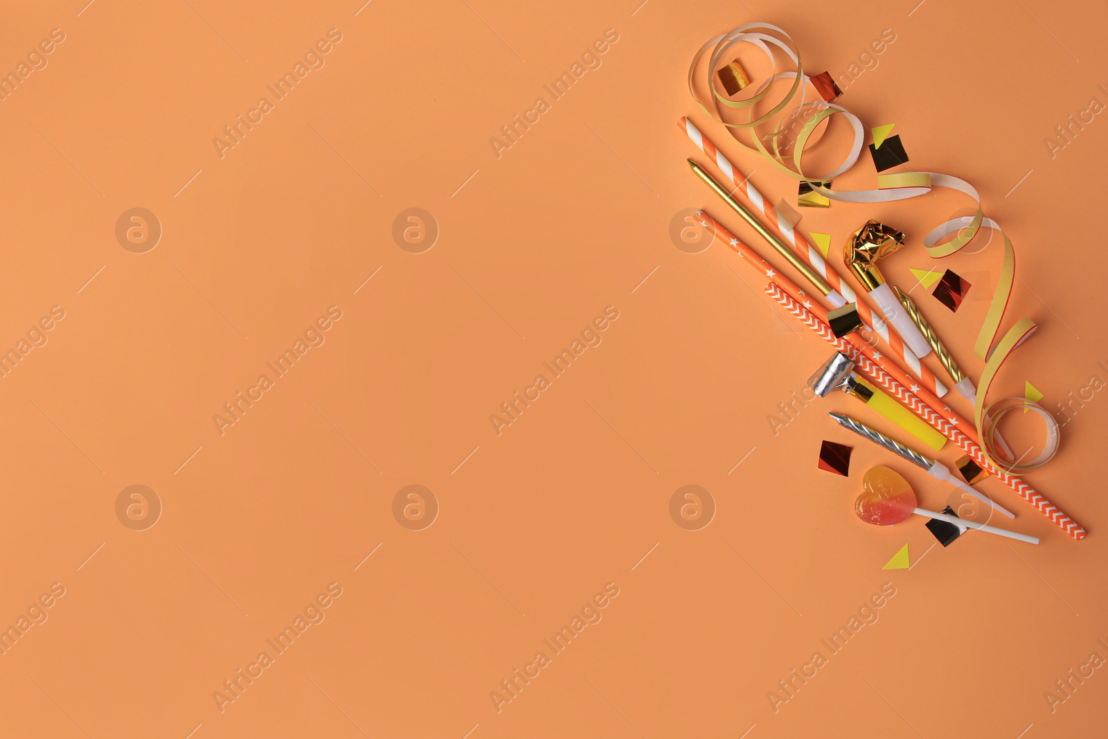 Photo of Party blowers, lollipop and festive decor on coral background, flat lay. Space for text