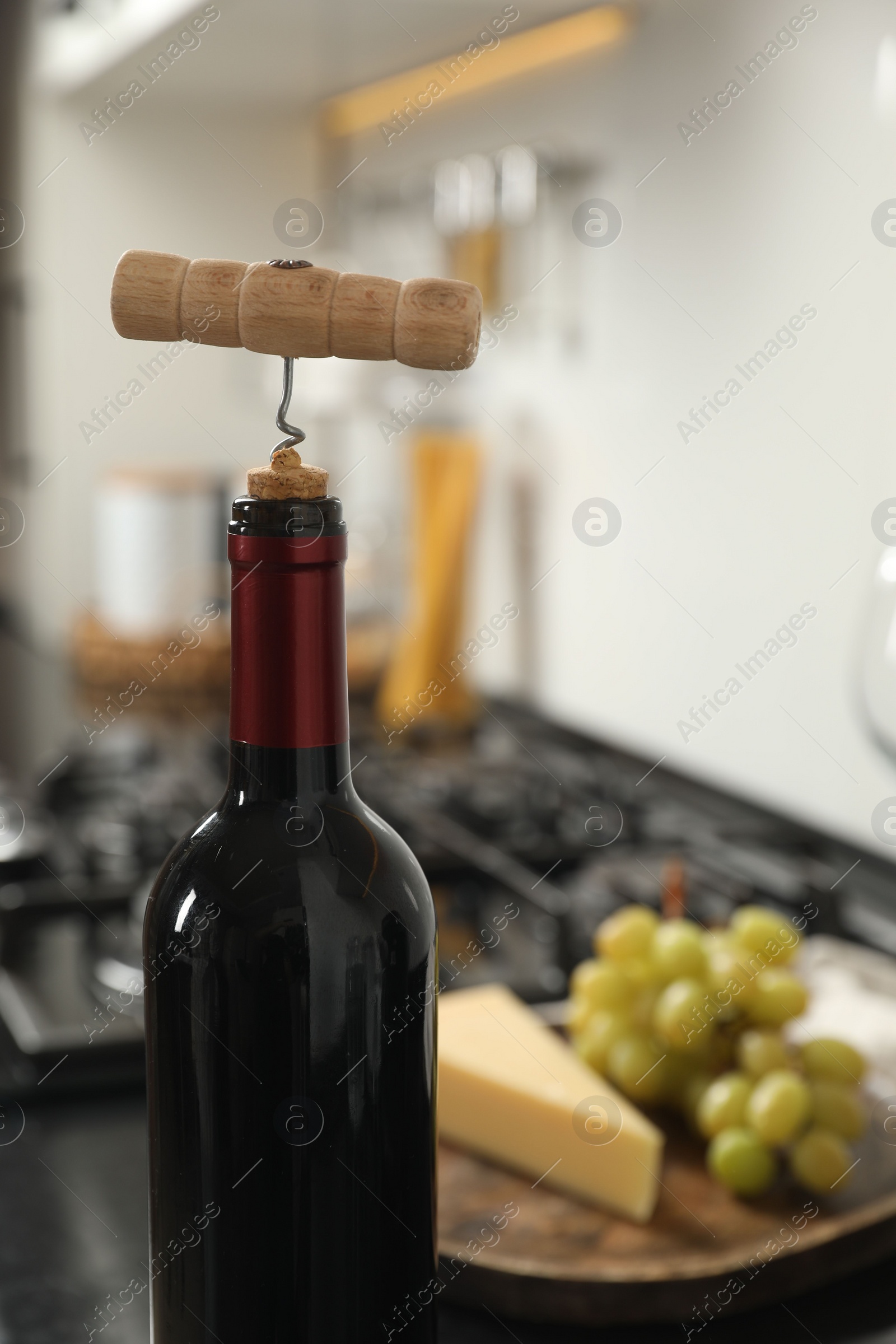 Photo of Wine bottle with corkscrew in kitchen, closeup. Space for text