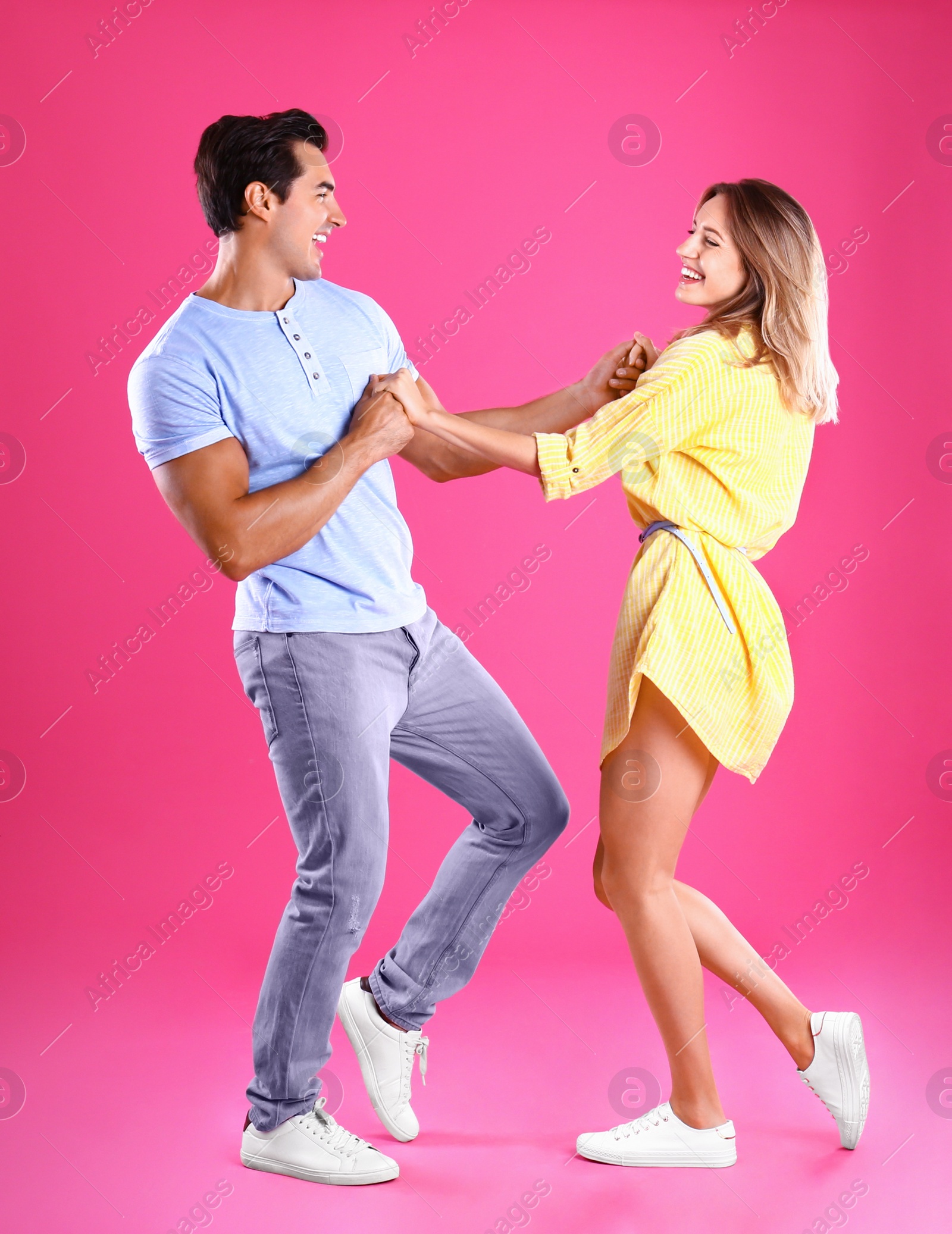 Photo of Beautiful young couple dancing on pink background