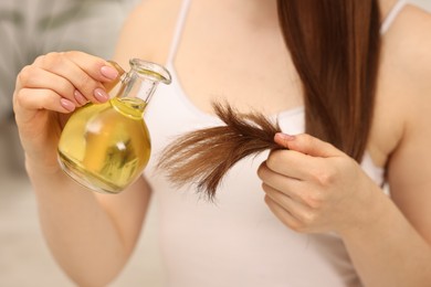 Photo of Woman applying oil hair mask at home, closeup