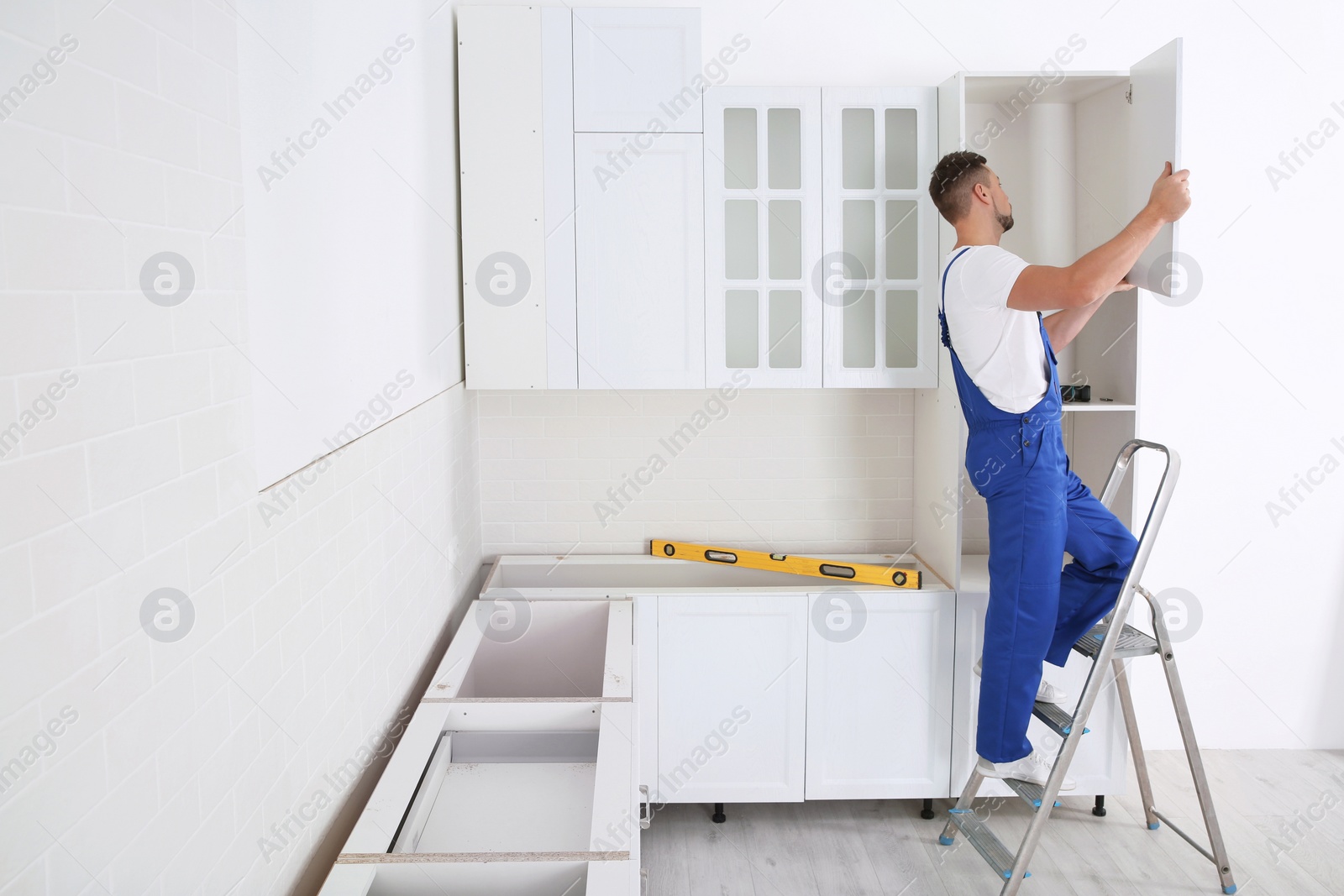 Photo of Worker installing door of cabinet in kitchen