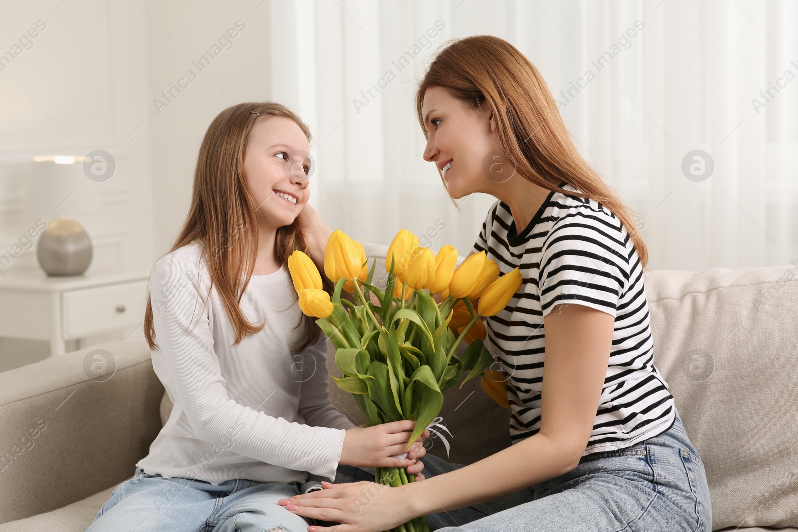 Photo of Daughter congratulating mom with bouquet of yellow tulips at home