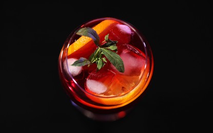 Photo of Glass of delicious refreshing sangria on black table, above view