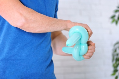 Photo of Man making balloon figure on blurred background, closeup