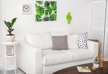 Stylish modern room interior with picture of tropical leaves on wall