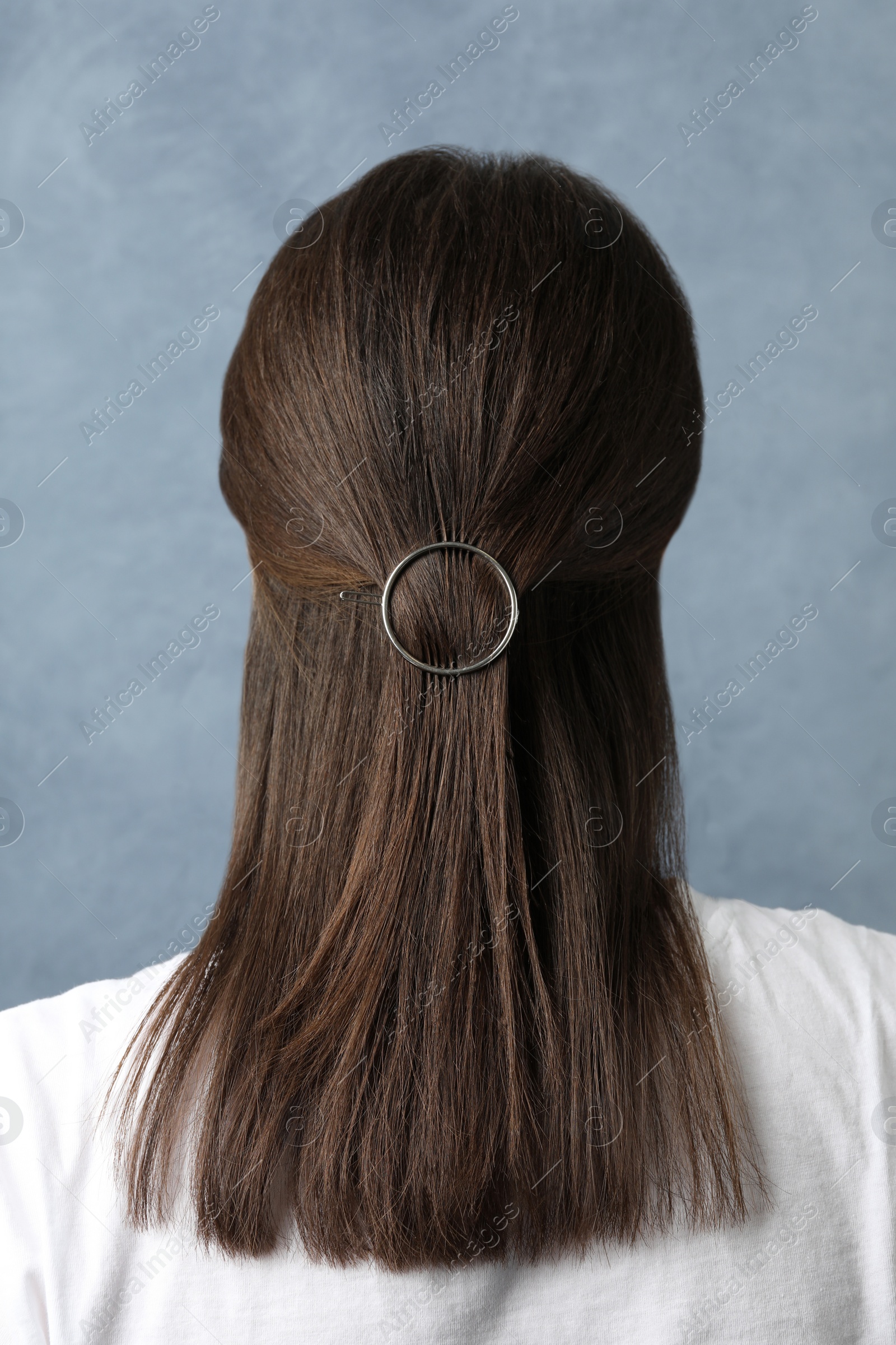 Photo of Young woman with beautiful hair clip on blue background, back view