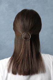 Photo of Young woman with beautiful hair clip on blue background, back view