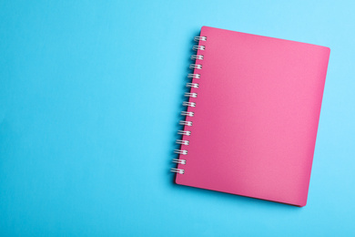 Stylish pink notebook on light blue background, top view. Space for text