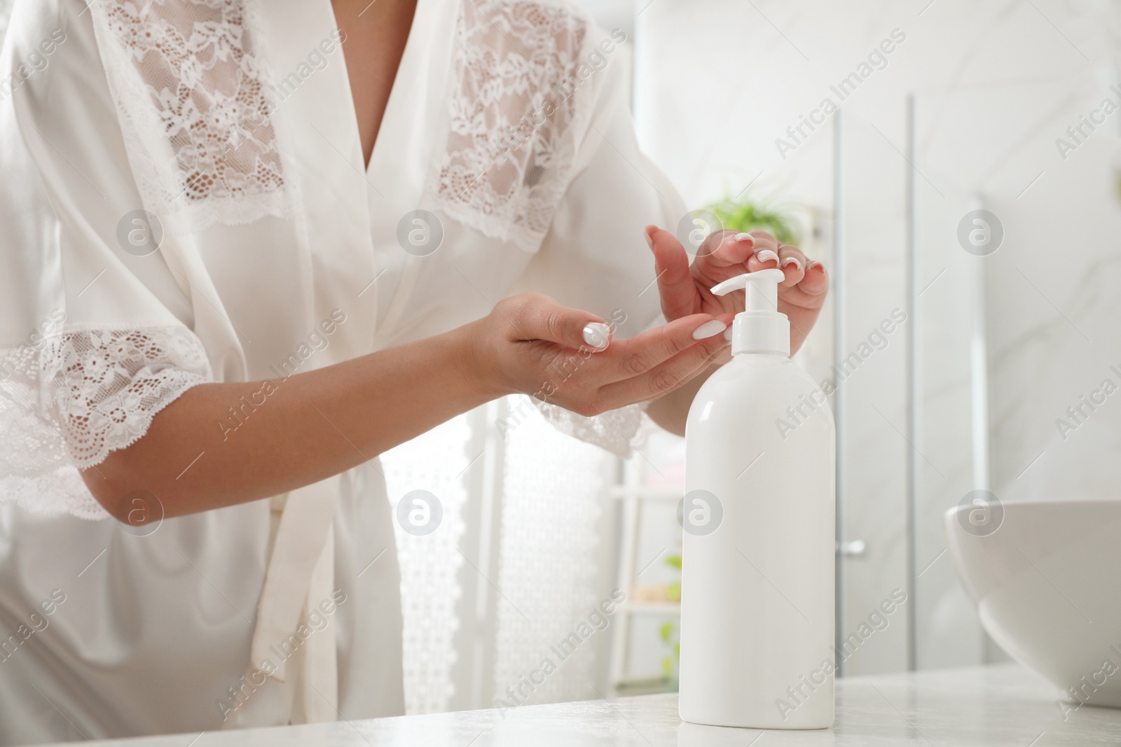 Photo of Beautiful young woman using washing gel in bathroom, closeup. Skin care cosmetic