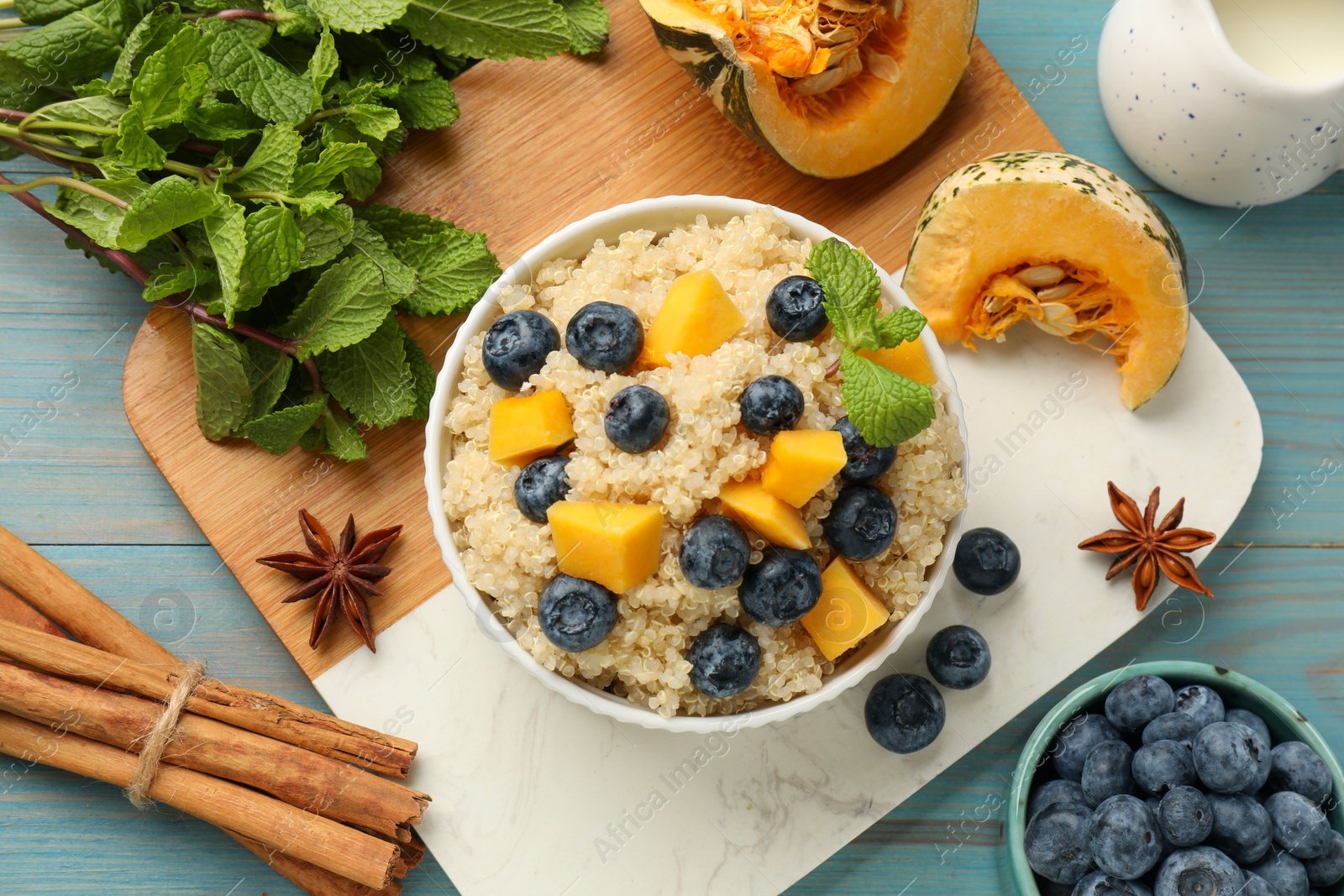 Photo of Flat lay composition with bowl of tasty quinoa porridge on light blue wooden table