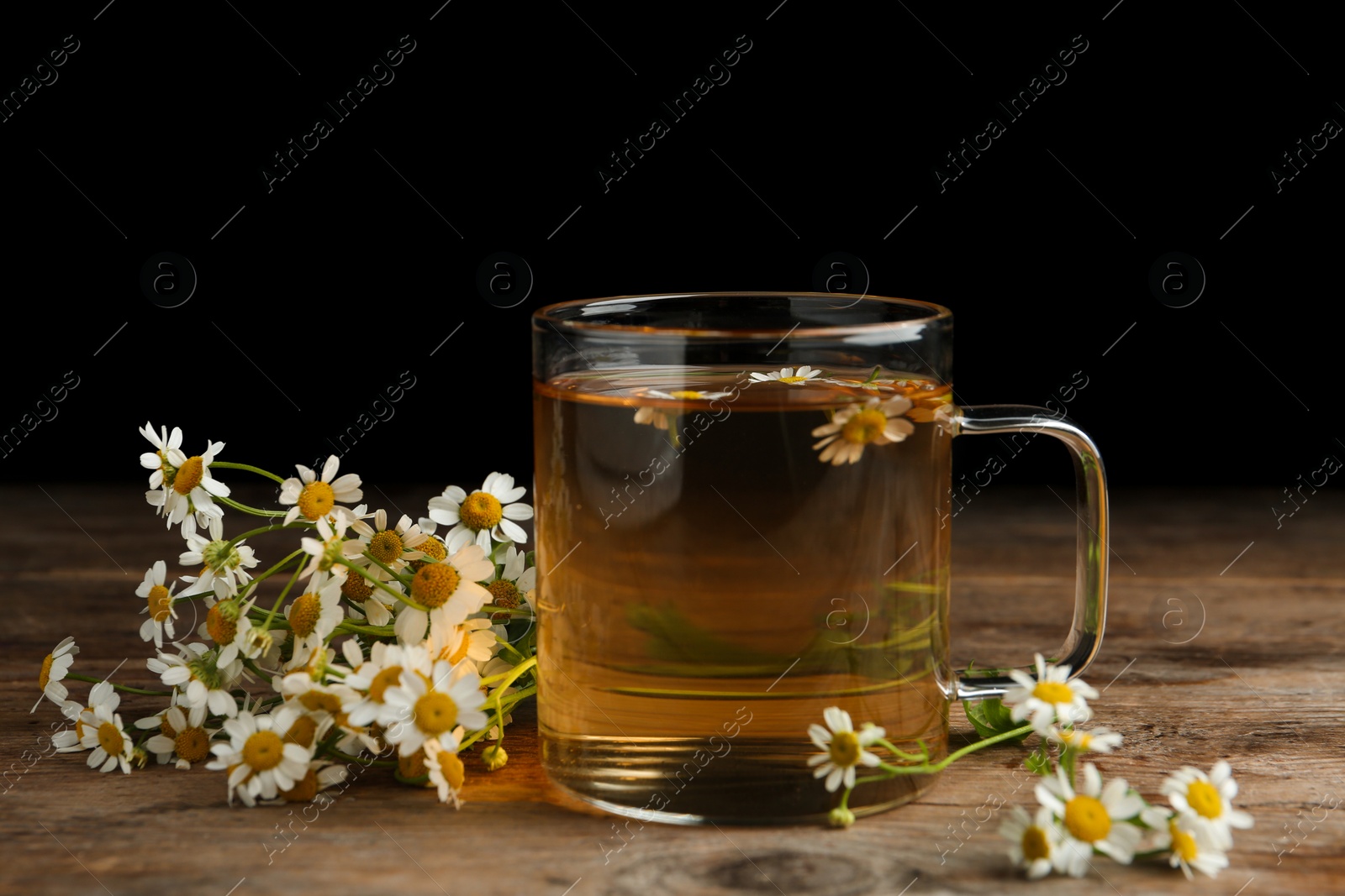 Photo of Cup of tea and chamomile flowers on wooden table