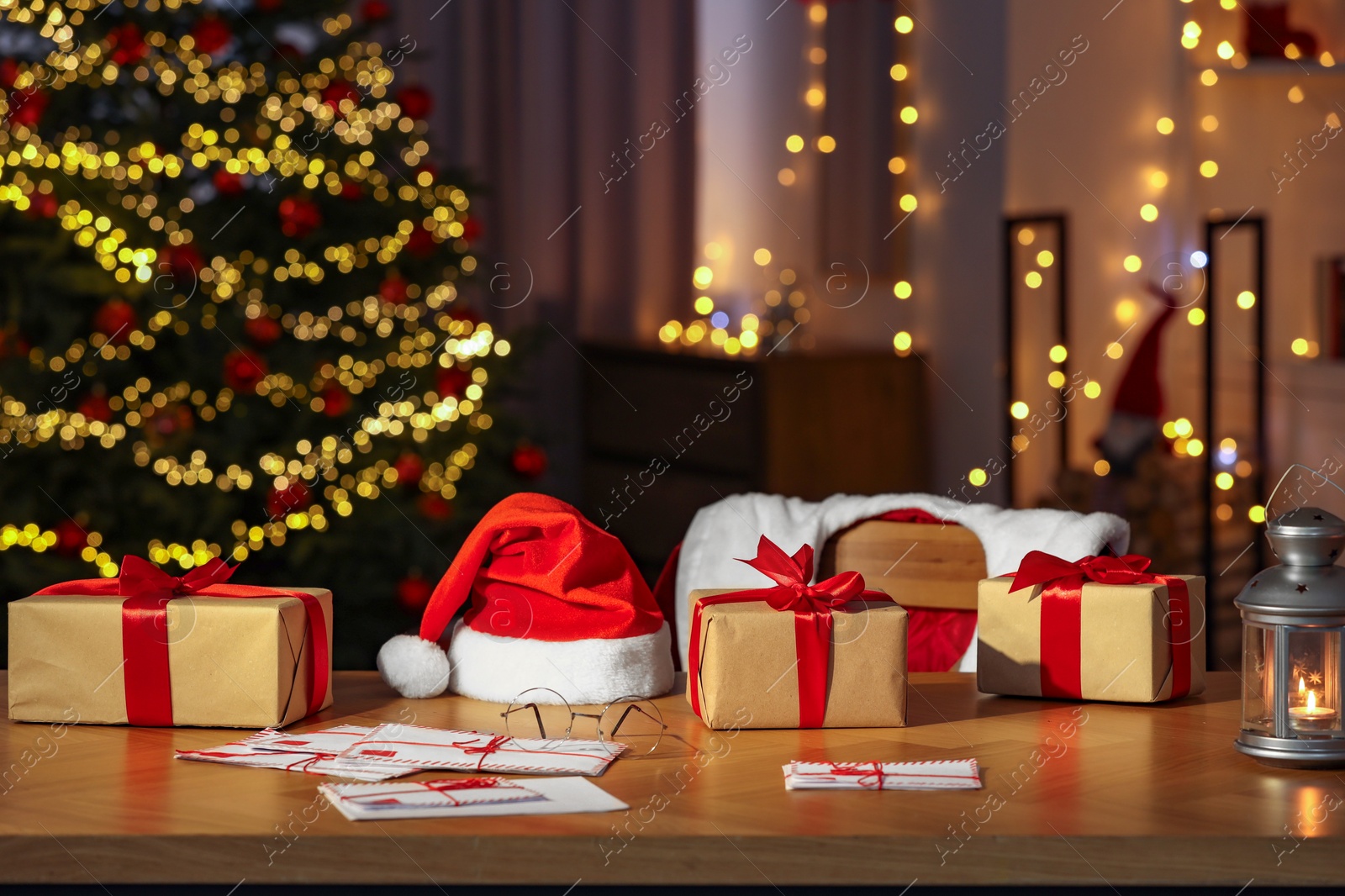 Photo of Santa's Claus workplace. Gift boxes, letters, lantern on table and costume in room with Christmas decor