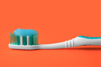 Photo of Brush and toothpaste on orange background, closeup
