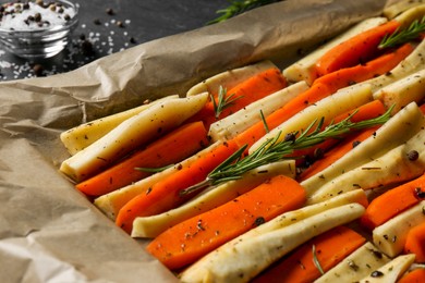 Photo of Slices of parsnip and carrot with rosemary on baking tray, closeup