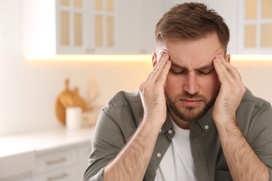 Photo of Man suffering from migraine at home, space for text
