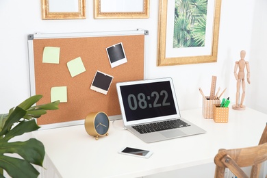 Photo of Stylish workplace with laptop on table in room